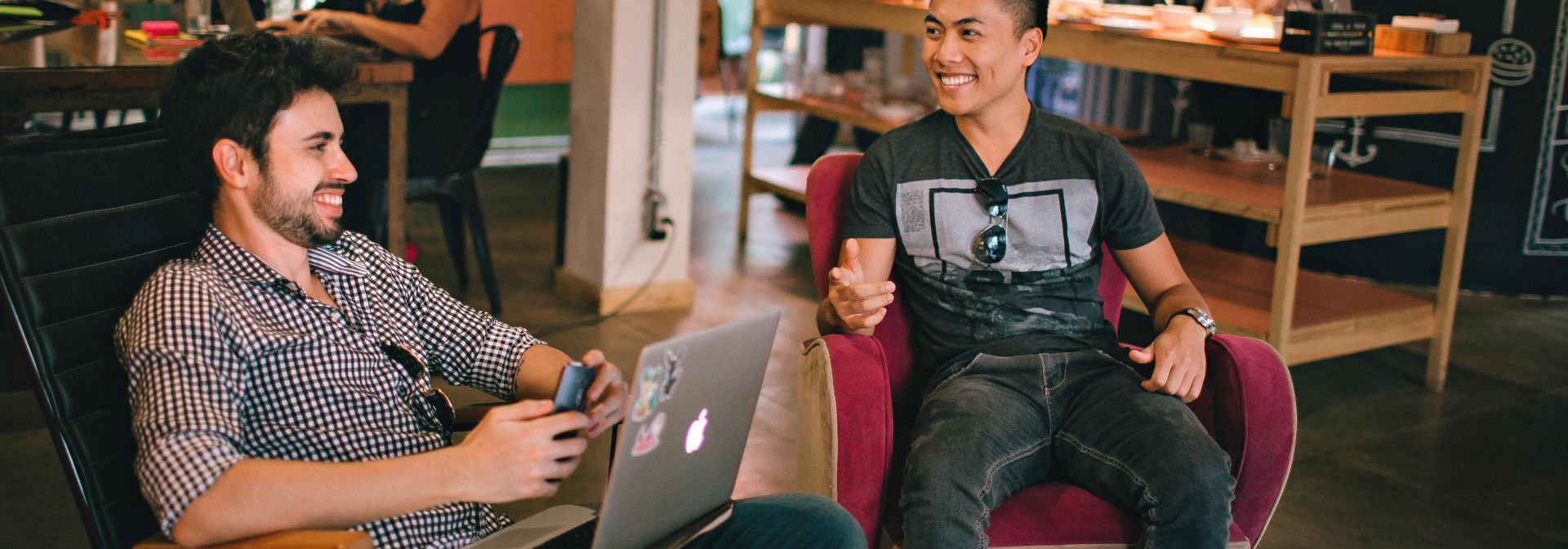 Two men enjoying a relaxed conversation with laptops in a cozy Brazilian café.