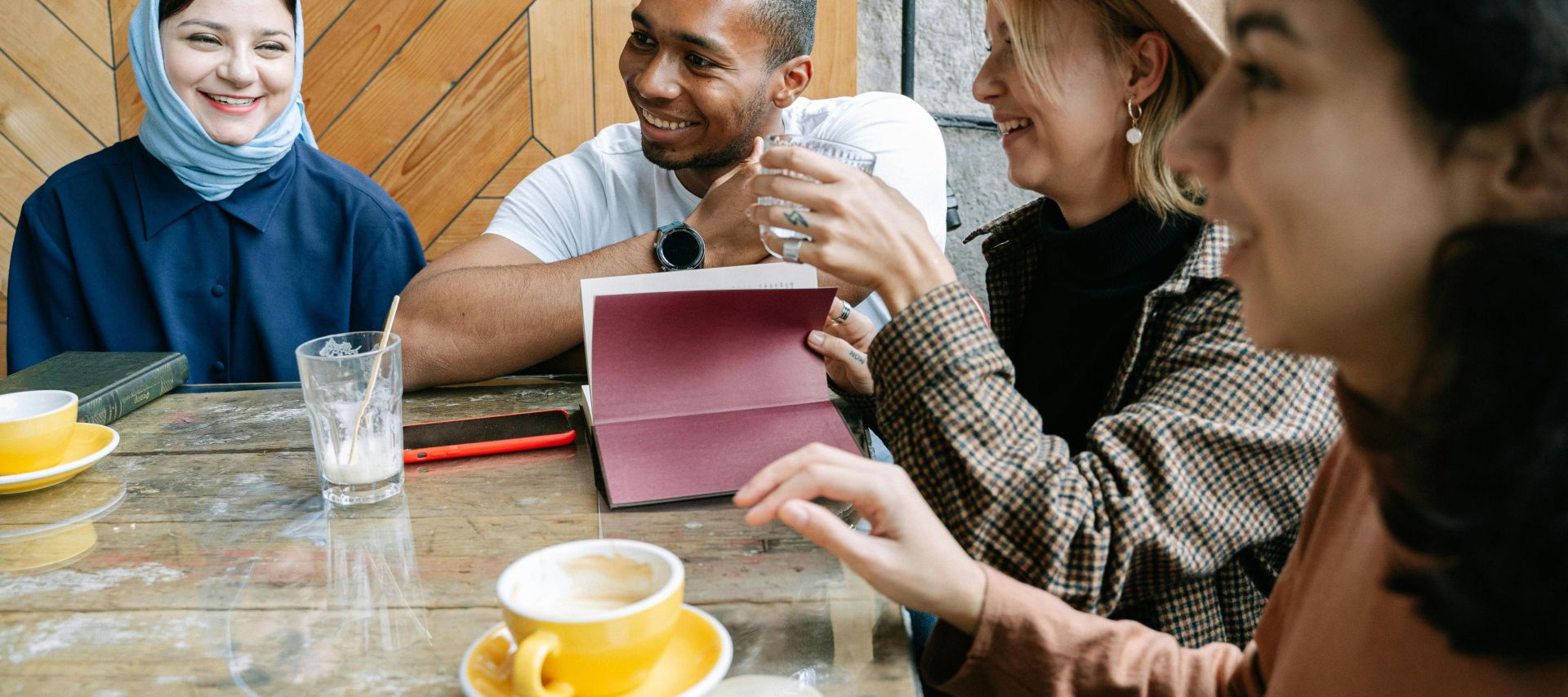 A group of friends sharing a joyful moment over coffee inside a cozy cafe.
