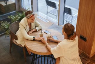Two women sharing a joyful moment over iced coffee at a stylish café.