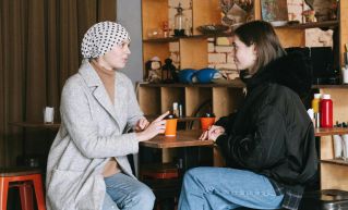 Two women having a conversation in a cozy café setting with warm winter clothing.